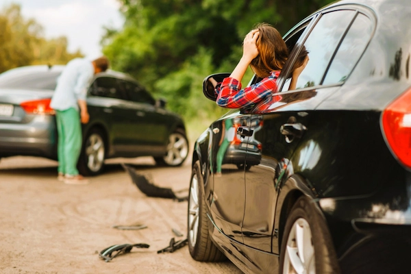 Accidente de tráfico entre coches con conductora preocupada, representando indemnización por accidente in itinere laboral