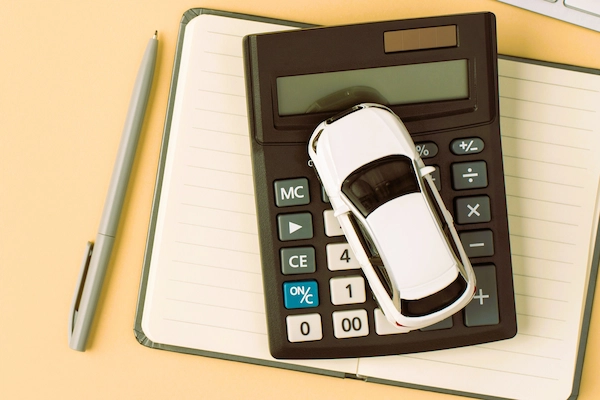 Calculadora con coche en miniatura sobre libreta, representando si aceptar oferta motivada y seguir reclamando en accidentes