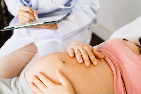 Mujer embarazada siendo evaluada por médico, ilustrando asfixia perinatal por negligencia médica durante el parto