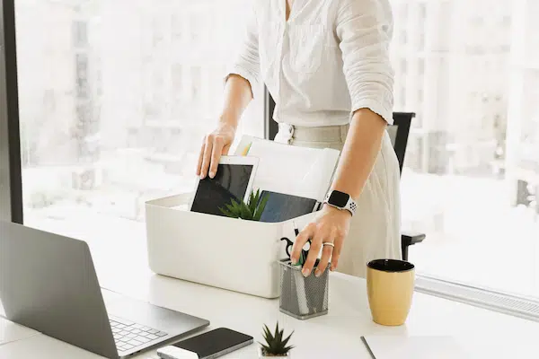 Persona recogiendo objetos de oficina tras un ERE, despido colectivo que implica la extinción de contratos laborales.