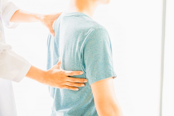 Paciente con dolor lumbar siendo examinado, relacionado con incapacidad laboral por espondilosis lumbar, desgaste de la columna.