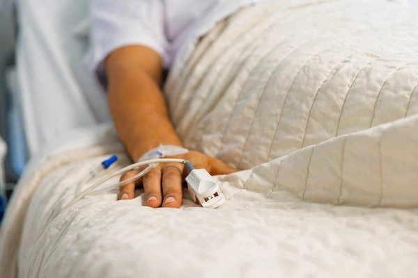 Paciente hospitalizado con vía intravenosa, representando sepsis y posibles negligencias médicas por infección grave