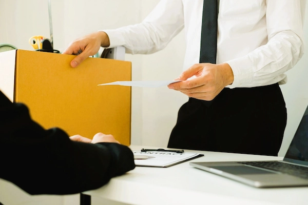 Trabajador entregando carta de despido objetivo e indemnización laboral en oficina de empresa