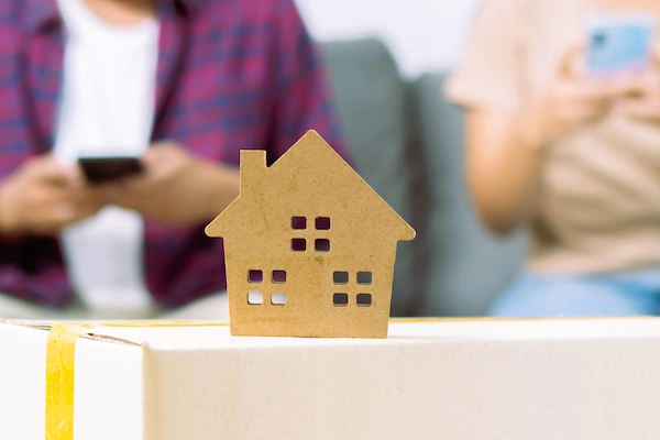 Maqueta de una vivienda frente a una pareja que simboliza la vivienda familiar en la liquidación de gananciales.