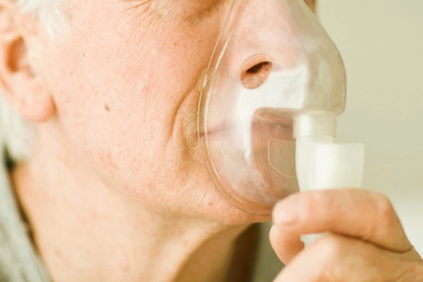 Paciente mayor utilizando mascarilla de oxígeno relacionado con casos de anoxia y negligencias médicas.