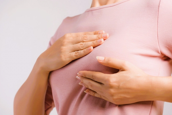 Mujer sujetando el pecho tras una mastectomía, intervención para extirpar tejido mamario, relacionada con posibles negligencias médicas.