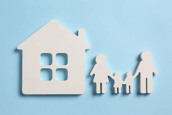 Familia junto a una casa, símbolo del uso y disfrute de la vivienda familiar y de cuánto puede durar este derecho tras una ruptura.